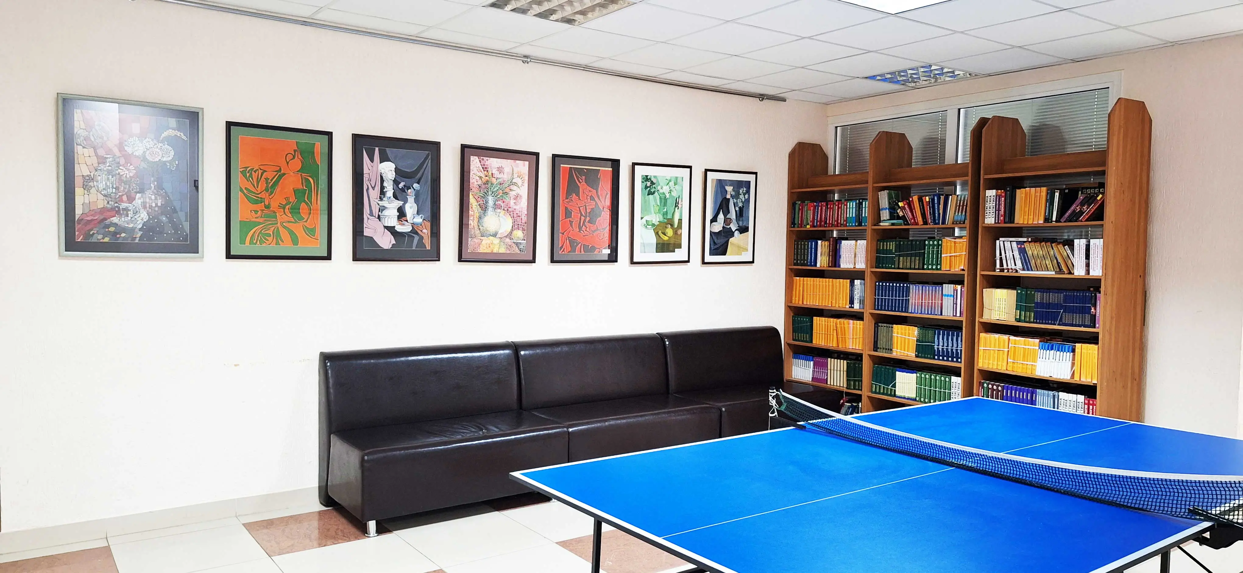 Фотография коридора с книжными стеллажми, теннисным столом, картинами основного корпуса